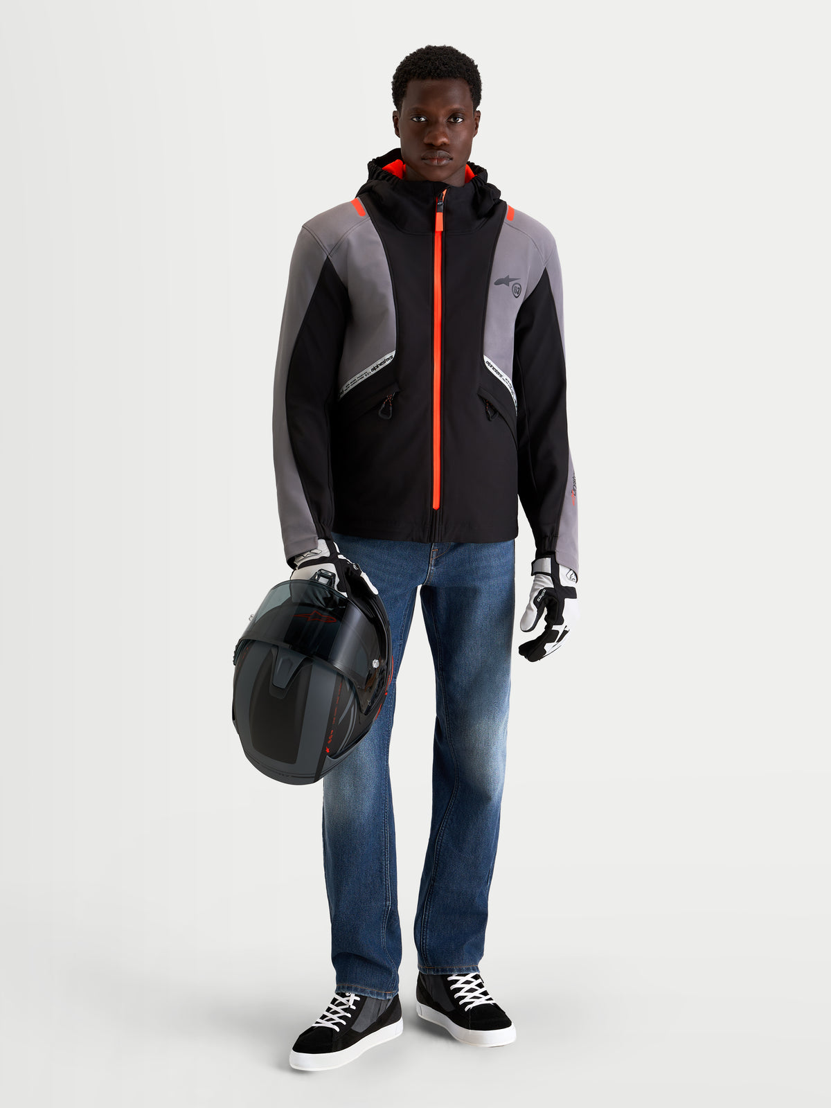 Alpinestars Flex Ast 8 Denim spodnie motocyklowe męskie urban contemporary, średnio niebieskie, na modelu trzymającym kask w czarno-szarej kurtce technicznej