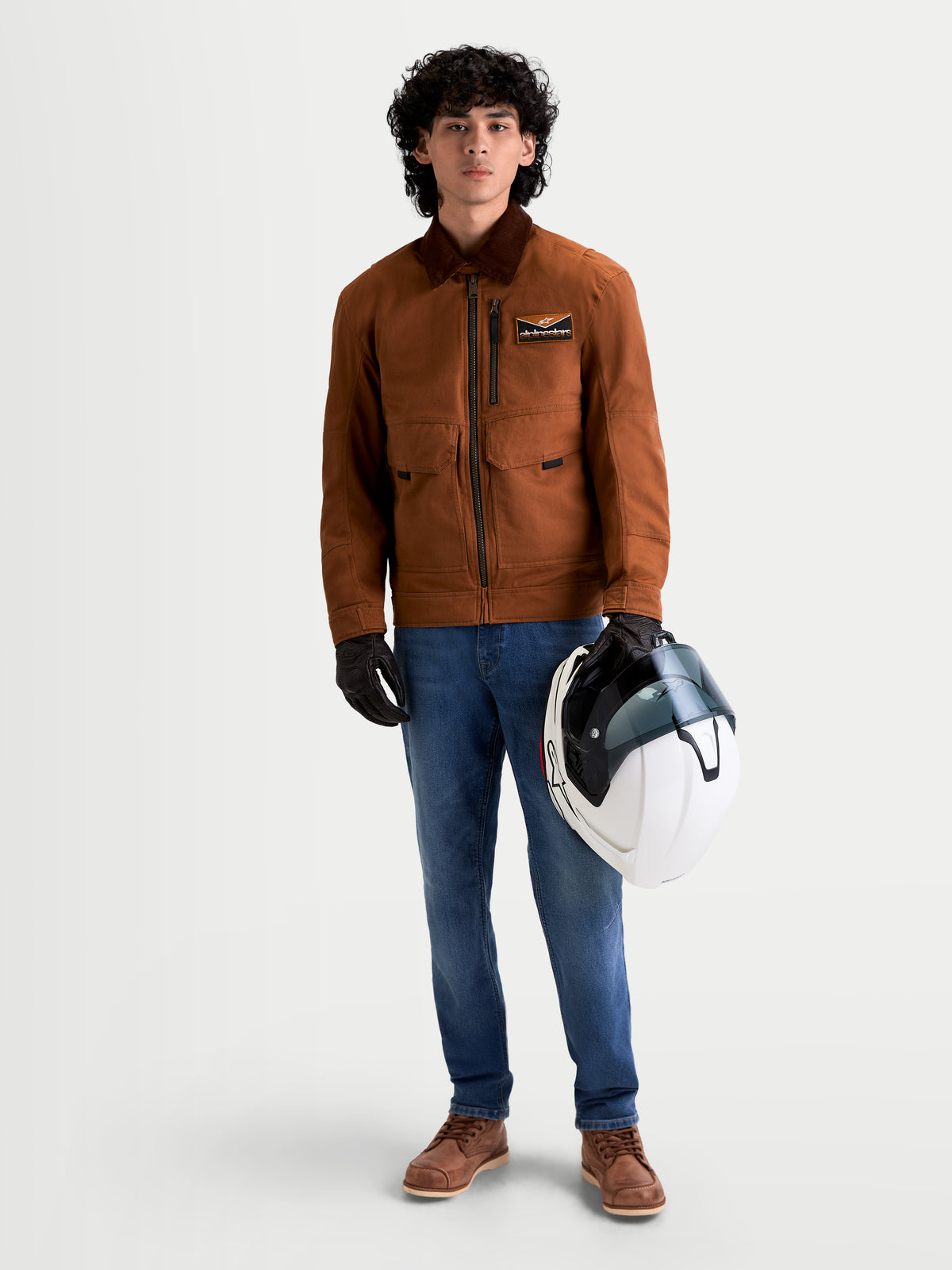 Alpinestars Flex Ast 7 Denim Spodnie Short, męskie miejskie współczesne jeansy motocyklowe w kolorze jasnoniebieskim, na modelu w brązowej kurtce trzymającym kask, certyfikowane techniczne jeansy AA