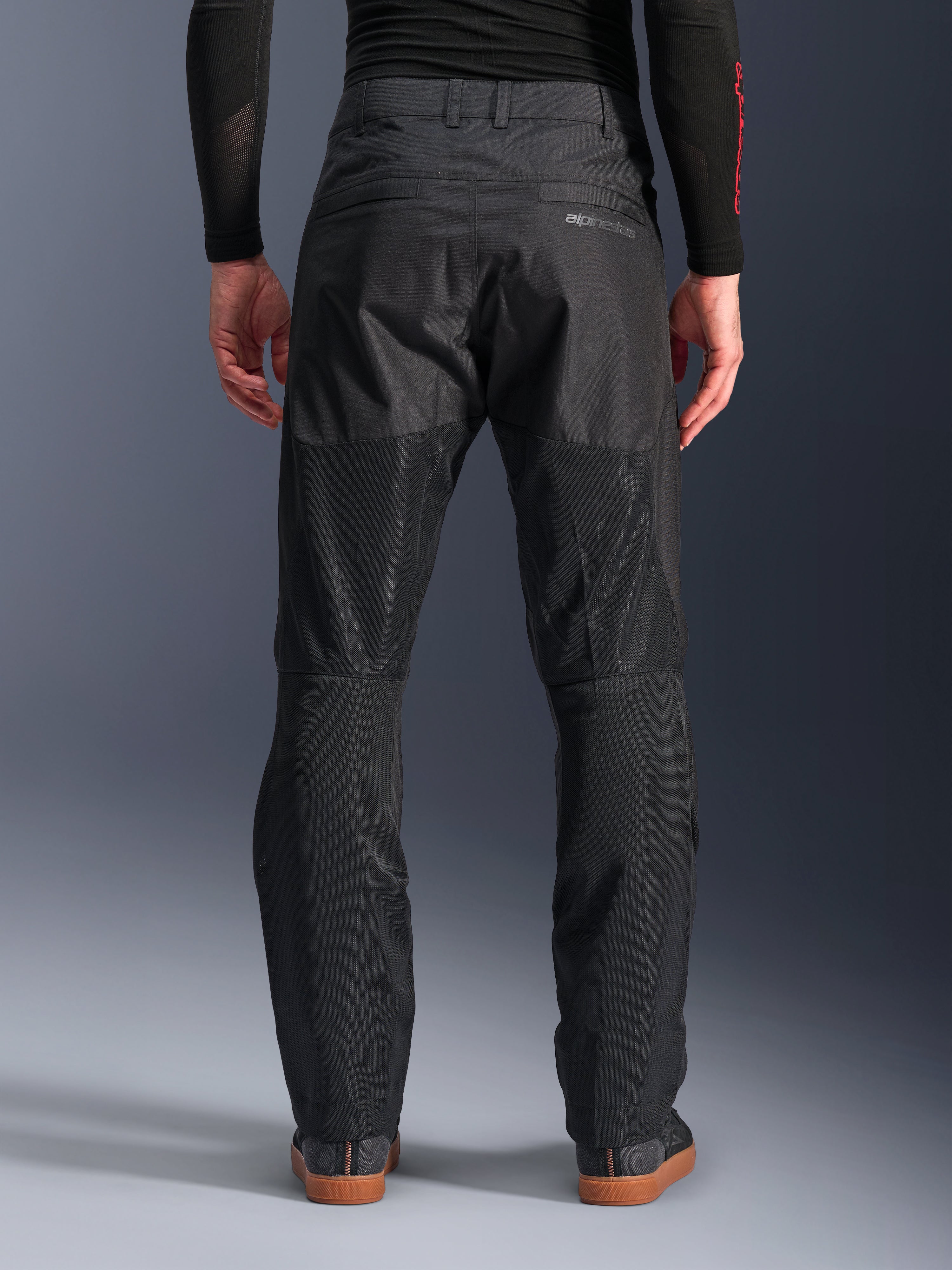 Alpinestars C-1 Air Pants, back view, Black, urban textile motorcycle pants featuring large tech mesh panels on the back of the legs for ventilation, clean design with subtle branding, worn with a black base layer and casual riding shoes.