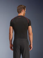 Widok z tyłu modela w spodniach Alpinestars Aeroshell Airflow, czarne, lekka konstrukcja softshell ze zintegrowanymi bocznymi panelami z siatki, w połączeniu z czarną warstwą bazową z czerwonymi kontrastowymi szwami, sportowy strój motocyklowy