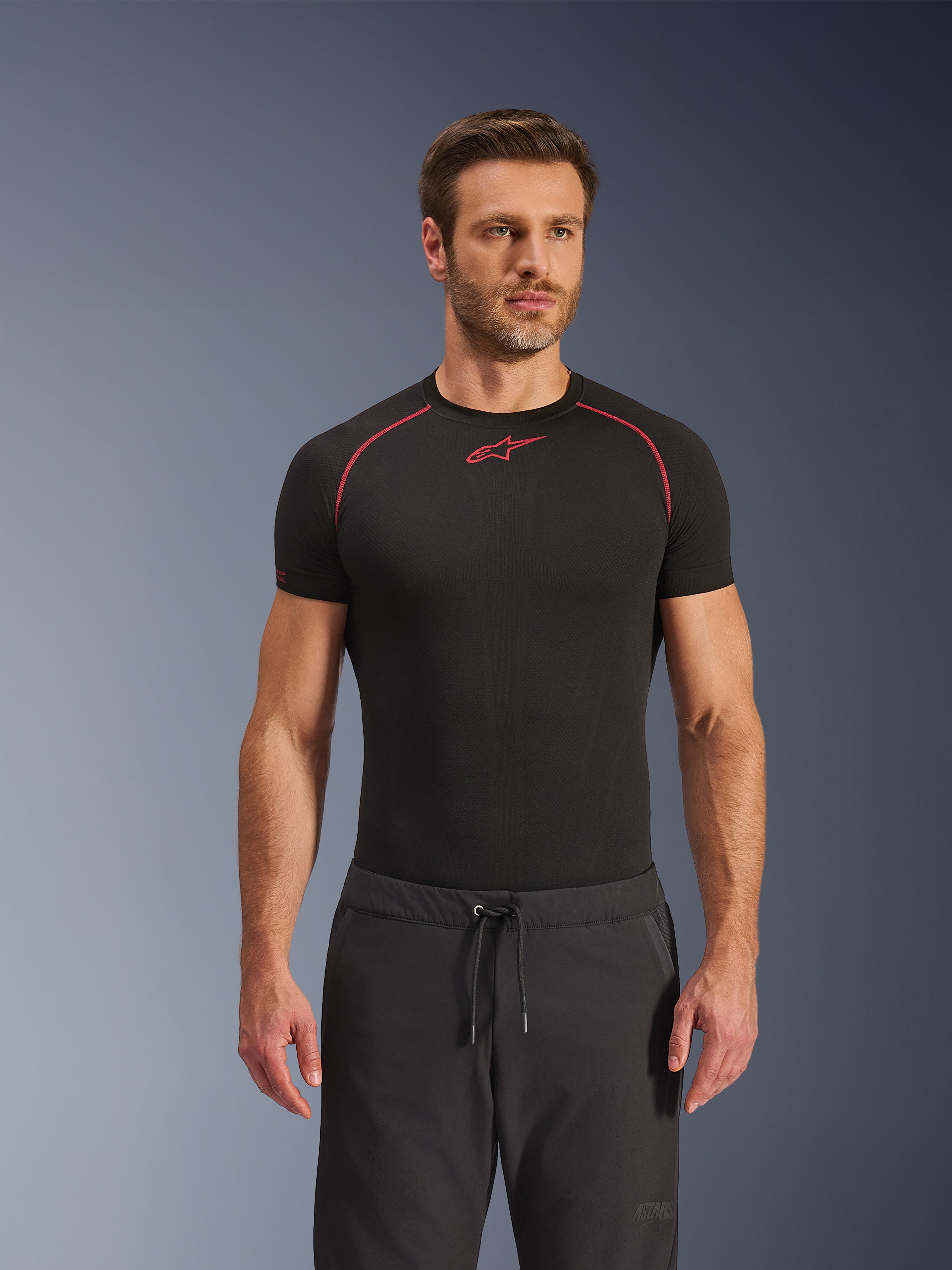 Spodnie Alpinestars Aeroshell Airflow, czarne spodnie motocyklowe, lekki materiał softshell, wyposażone w pas ze sznurkiem i laserową perforację dla wentylacji, zestawione z czarną koszulką termoaktywną Alpinestars