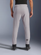 Alpinestars Aeroshell Airflow Pants, spodnie motocyklowe, Mid Gray, widok od tyłu ukazujący laserowo perforowane strefy na łydkach i czarne logo Astars, tekstylna konstrukcja softshell z czarnymi mankietami na kostkach i siatkowymi panelami na biodrach.