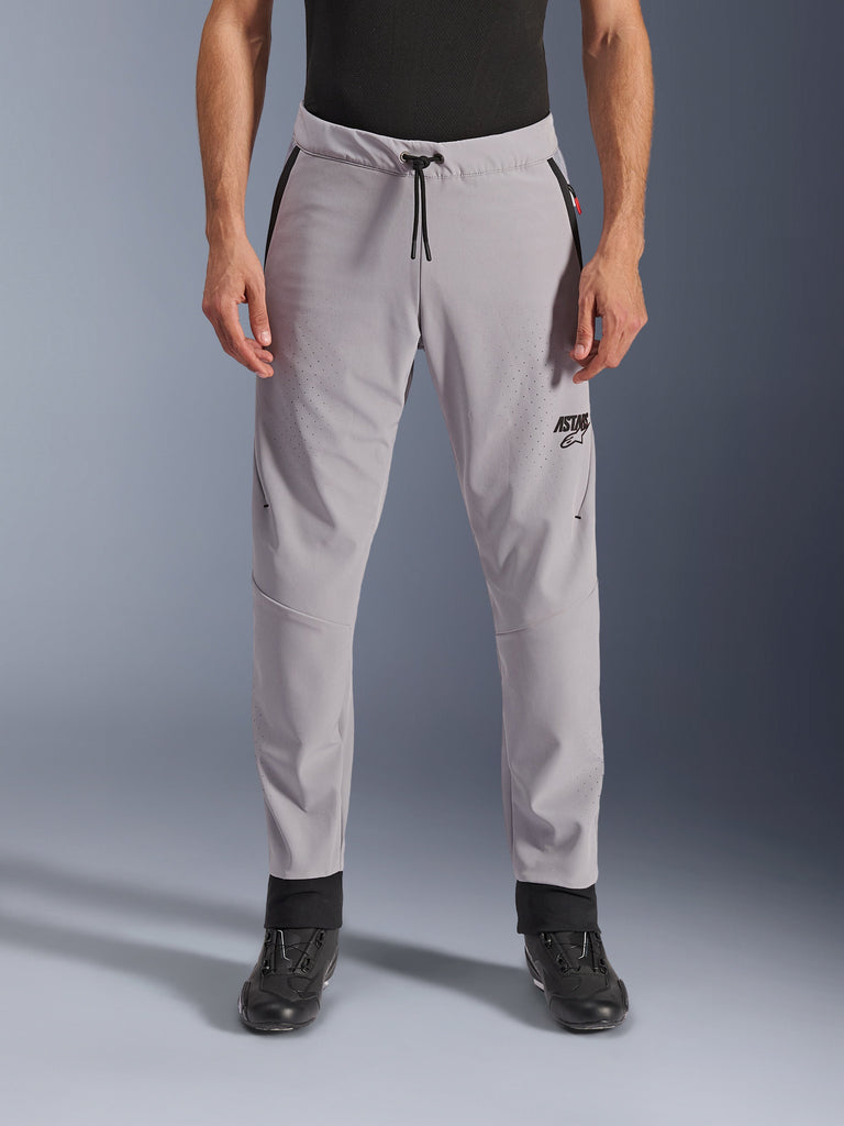 Alpinestars Aeroshell Airflow Pants, spodnie motocyklowe w kolorze Mid Gray, widok z przodu ukazujący strefy z laserowymi perforacjami na udach i goleniach, czarny sznurek w pasie i czarne logo ASTARS, lekka konstrukcja softshell do jazdy w ciepłe dni