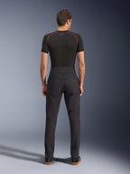 Alpinestars Flex-AST Canvas Pants, miejskie spodnie motocyklowe, czarne, widok z tyłu pokazujący design inspirowany odzieżą roboczą z tylnymi kieszeniami i podwyższonym tyłem, noszone z czarną warstwą bazową i sneakersami, ergonomiczny krój motocyklowy