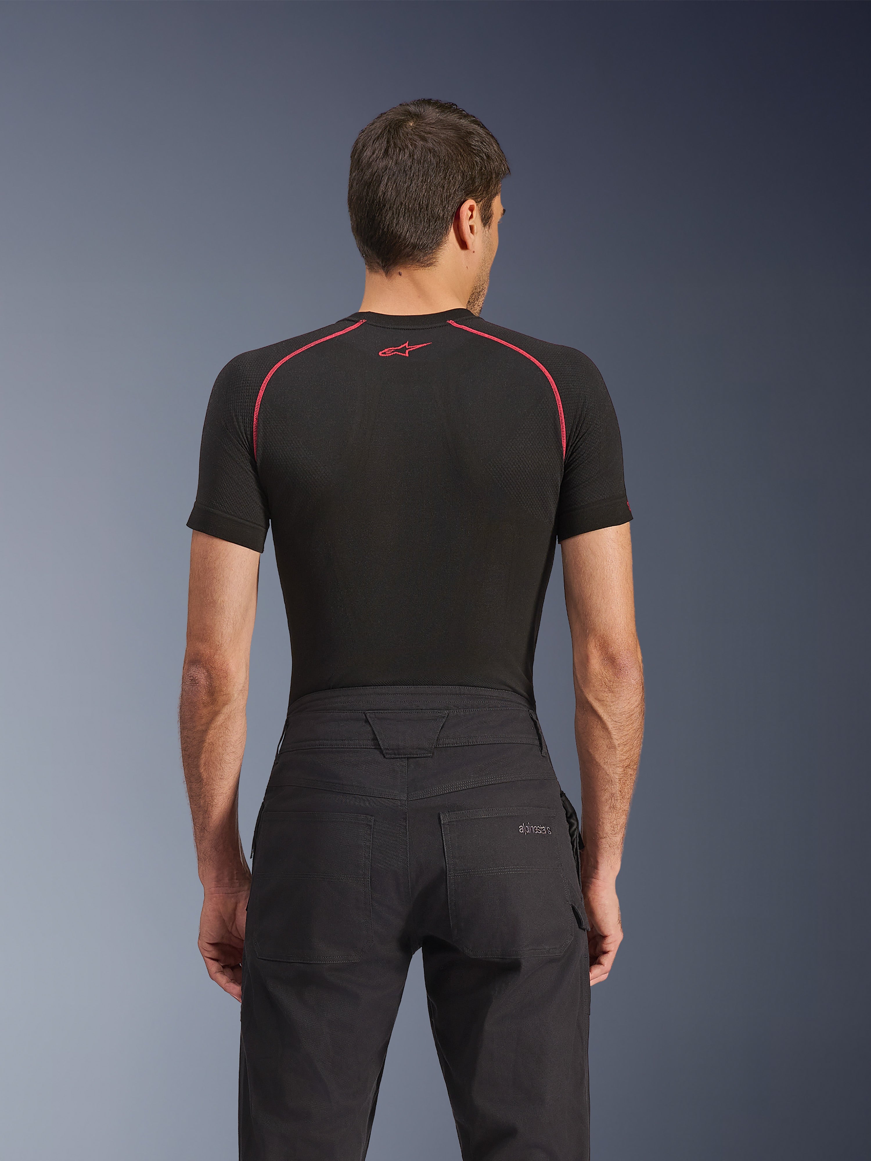 Alpinestars Flex-AST Canvas Pants, miejskie spodnie motocyklowe, czarne, widok z tyłu przedstawiający tylną kieszeń z haftowanym logo Alpinestars, wzmocniony pas i kontrastowe przeszycia, zestawione z czarną techniczną warstwą bazową.