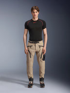 Męski model ubrany w spodnie Alpinestars Acteon w kolorze piaskowym (Sand), zestawione z czarną warstwą bazową z krótkim rękawem i czarnymi butami technicznymi, z kieszeniami cargo z czarnymi zamkami i zwężanym krojem, nowoczesna miejska odzież motocyklowa
