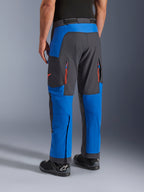 Alpinestars Maxdura Dual Pants, niebieskie i ciemnoszare, widok z tyłu przedstawiający kieszenie na zamek i strefy wentylacyjne, krój na buty noszony z czarnymi butami Alpinestars, wytrzymała odzież do jazdy adventure i dual-sport
