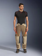 Alpinestars Maxdura Dual Pants, Adventure and Dual-Sport Riding Pants, Walnut Aluminum, worn with a black short-sleeve compression shirt and adventure boots, featuring orange zippered vents and red logos on the thighs, black waist belt with buckle, over-the-boot design for motorcycle riding.