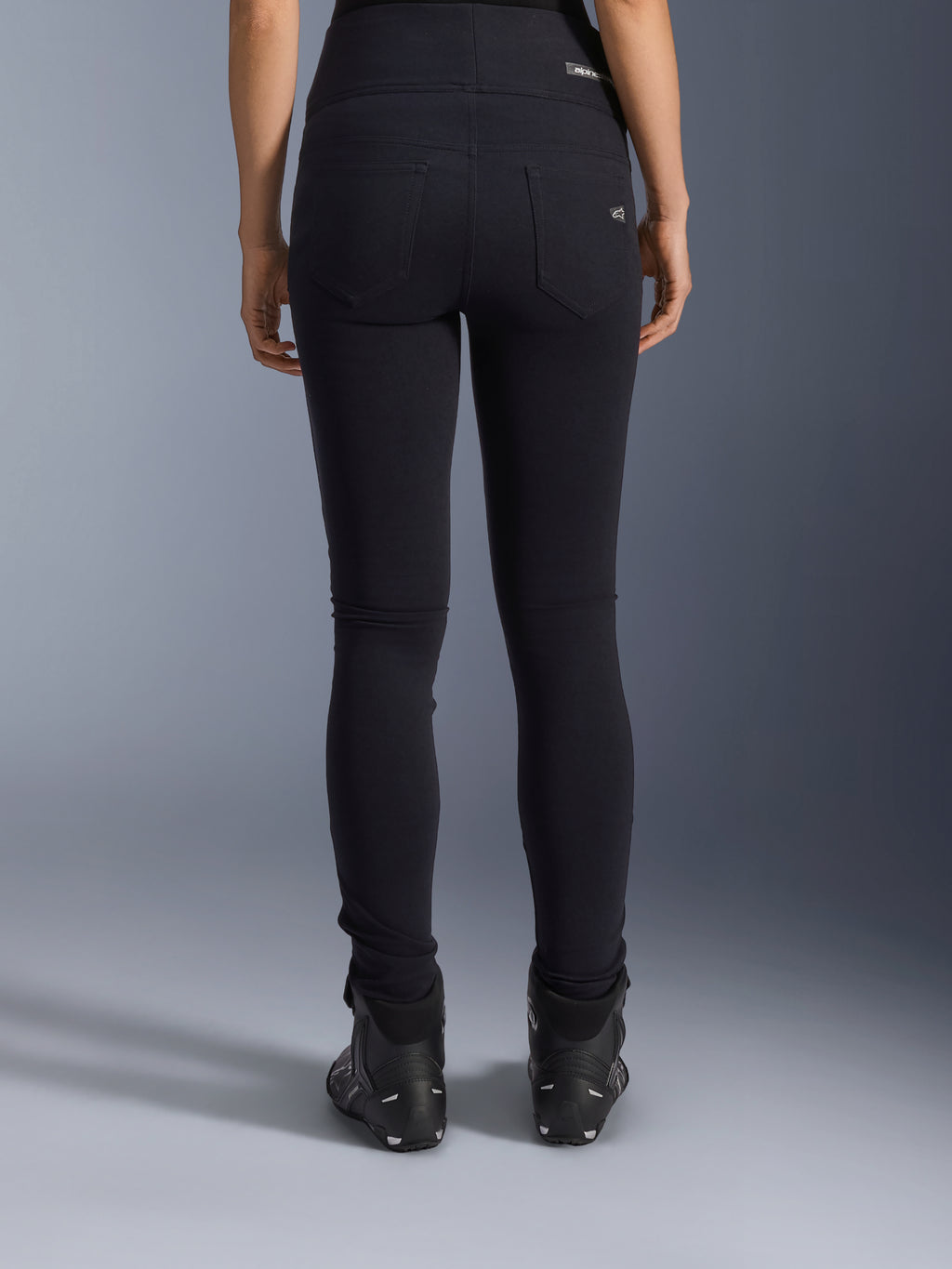 Legginsy Alpinestars Stella Flex-Ast, damskie legginsy motocyklowe, czarne, widok z tyłu ukazujący tylne kieszenie i dopasowany krój, noszone z czarnymi butami motocyklowymi, miejski styl jazdy