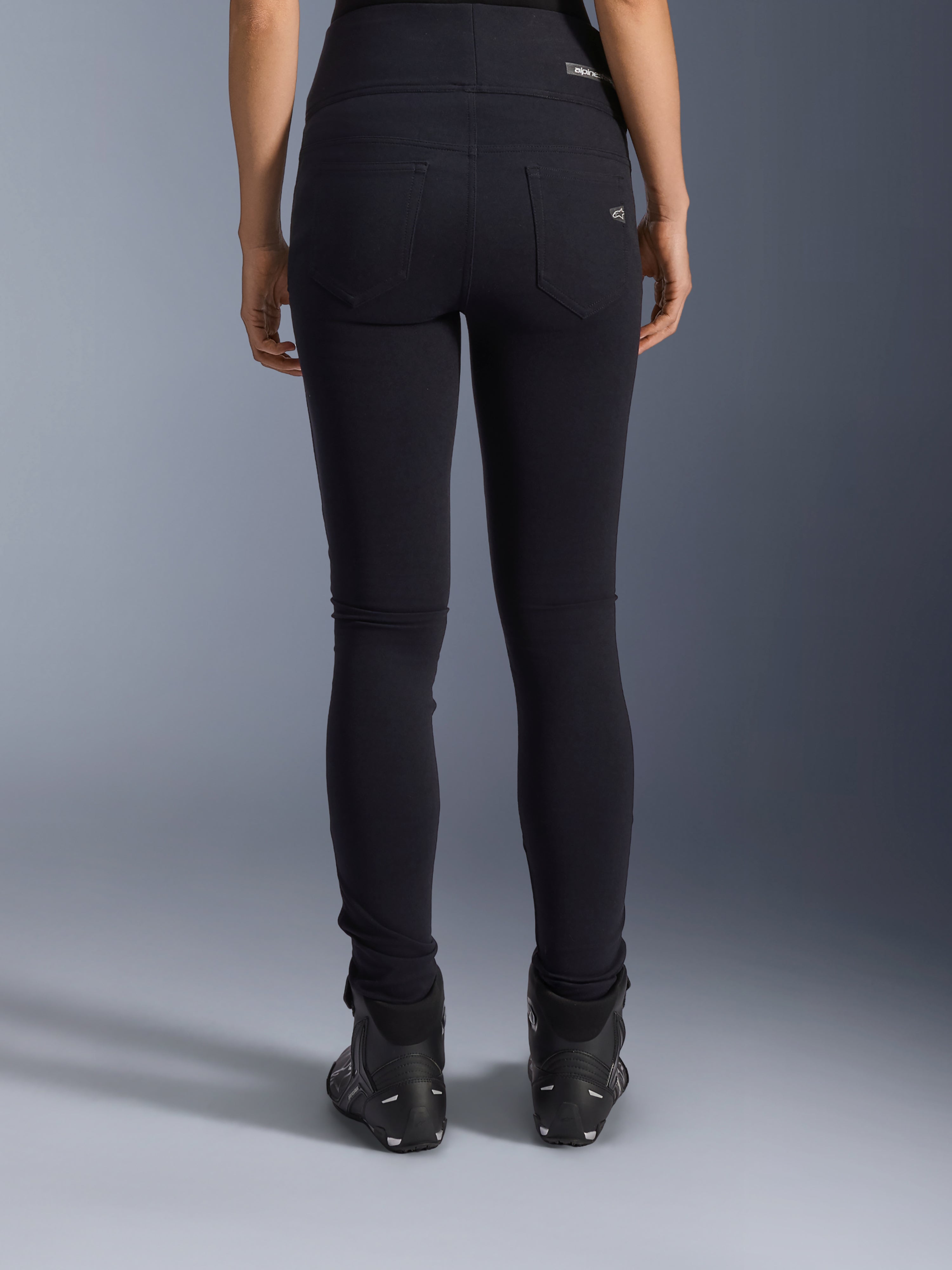 Legginsy Alpinestars Stella Flex-Ast, damskie legginsy motocyklowe, czarne, widok z tyłu ukazujący tylne kieszenie i dopasowany krój, noszone z czarnymi butami motocyklowymi, miejski styl jazdy