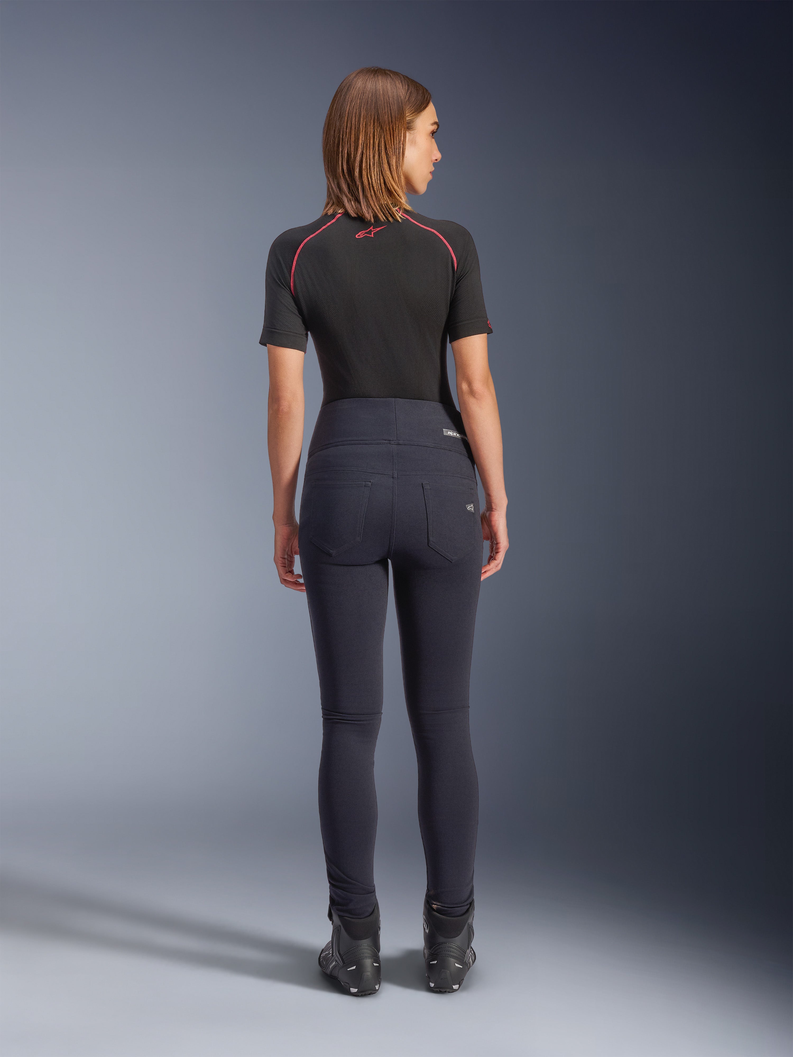 Legginsy Alpinestars Stella Flex-AST w kolorze czarnym, damskie spodnie motocyklowe z wysokim stanem, widok z tyłu prezentujący dopasowany krój i tylne kieszenie, noszone z czarnym topem z krótkim rękawem i butami motocyklowymi, miejska odzież motocyklowa