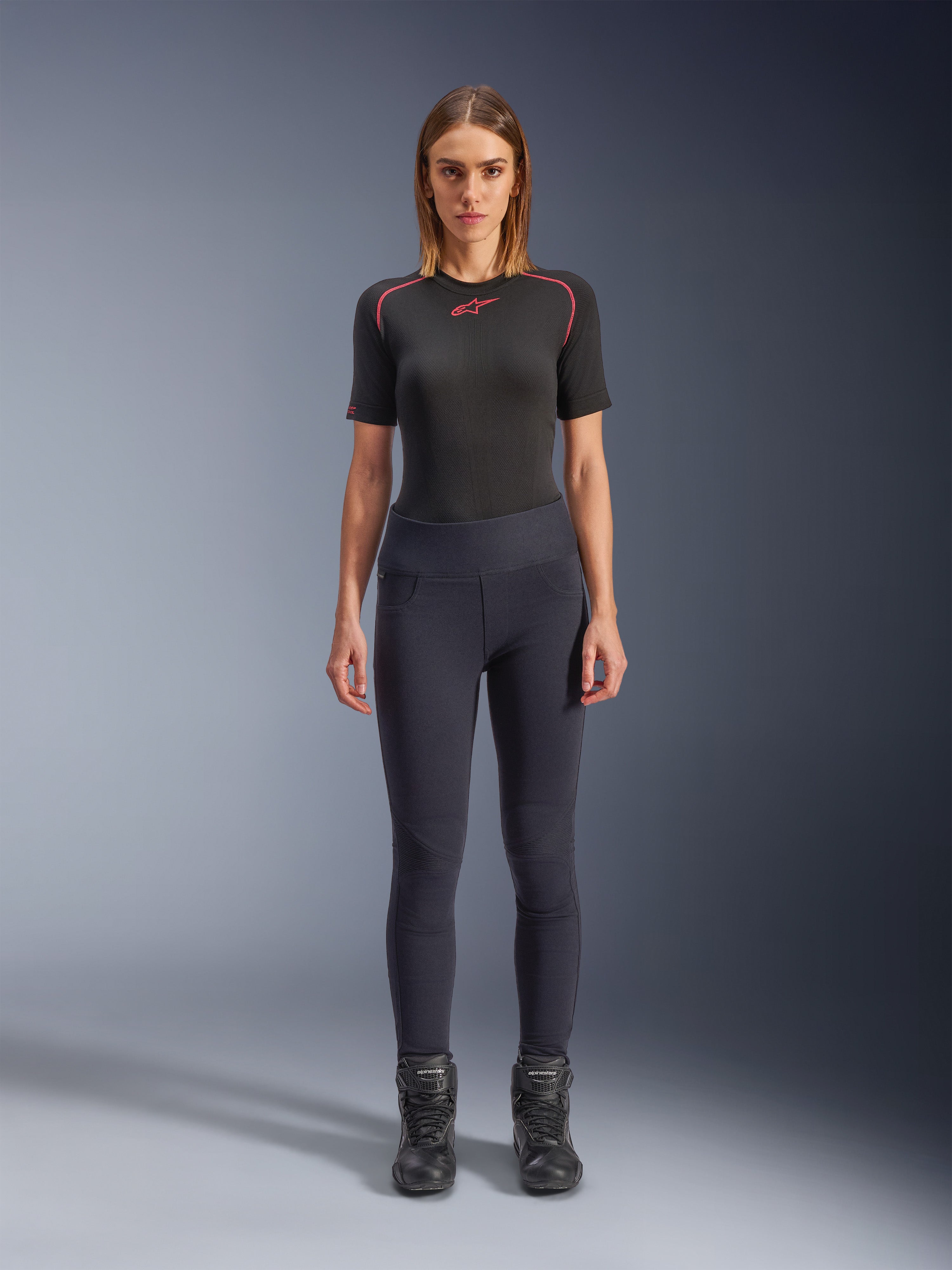 Alpinestars Stella Flex-AST Leggings, damskie miejskie legginsy motocyklowe w kolorze czarnym, dopasowany fason z wysokim stanem, zestawione z czarnym technicznym topem z krótkim rękawem i czarnymi butami motocyklowymi, z harmonijkowymi panelami na kolanach i nowoczesnym, minimalistycznym wyglądem