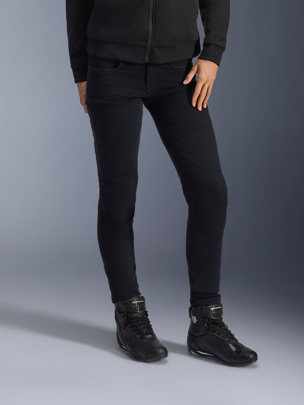 Alpinestars Daisy V3, damskie jeansy motocyklowe, Rinse Black, dopasowany krój slim-fit, w połączeniu z czarnymi wysokimi butami i rozpinaną bluzą z kapturem, nowoczesna monochromatyczna stylizacja miejska