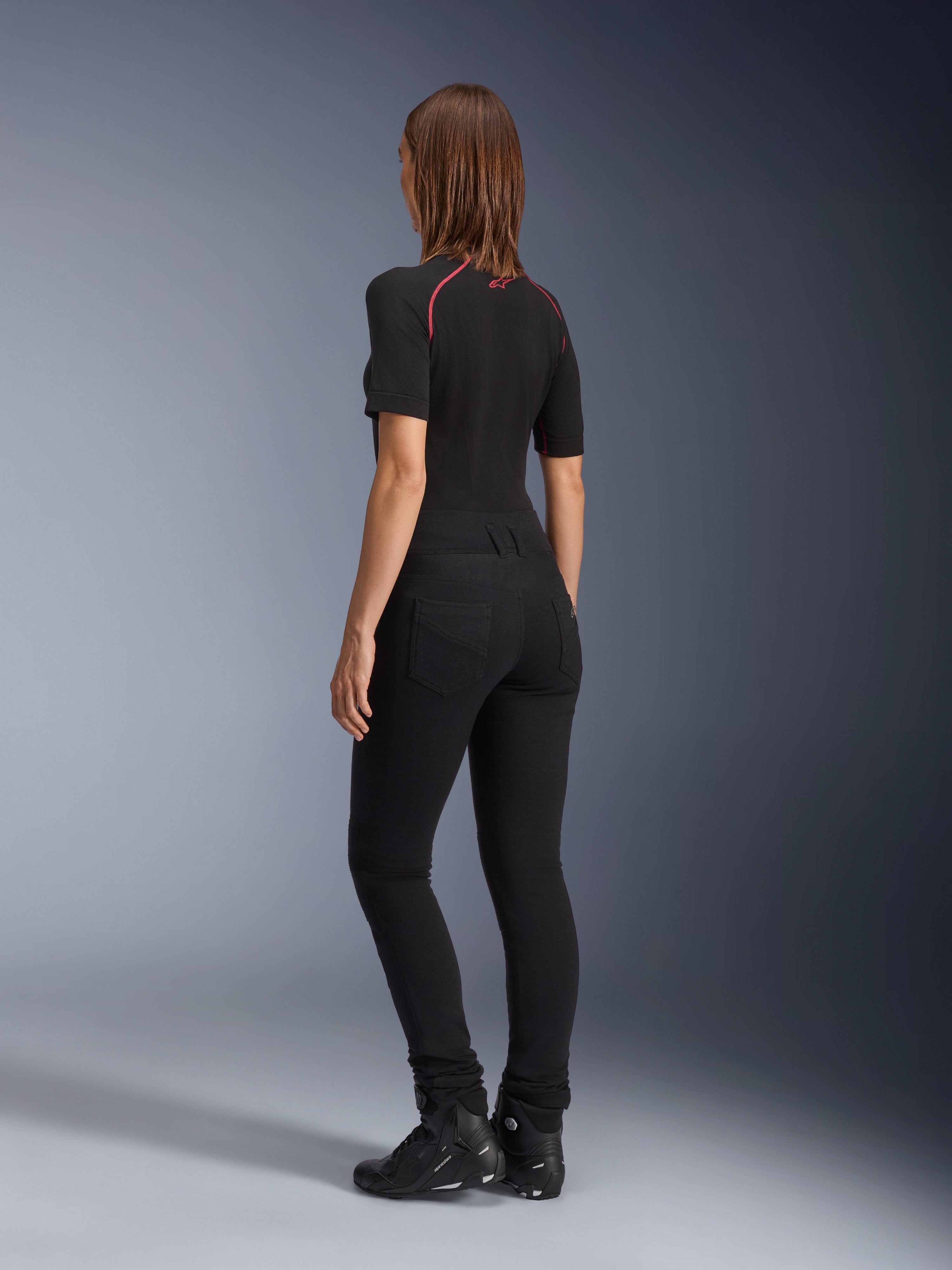 Legginsy damskie Alpinestars Banshee, czarne, widok z tyłu prezentujący dopasowany do sylwetki anatomiczny krój i tylne kieszenie, zestawione z czarną koszulką z krótkim rękawem i butami motocyklowymi, stylowa miejska odzież motocyklowa dla kobiet