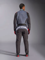 Alpinestars KMX-9 V3 Graphic 6 Suit, kombinezon kartingowy, antracytowa czerń i czerwień, widok z tyłu z dużym białym logo Alpinestars w dolnej części pleców, szara góra z czarną grafiką typu splatter, czarne rękawy i nogawki, noszony z czerwono-czarnymi rękawicami i butami wyścigowymi.