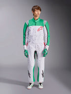 Alpinestars KMX-9 V3 Graphic 6 Suit, biało-zielono-czerwony, jednoczęściowy kombinezon kartingowy z czarnym wzorem graficznym typu splatter, zielone panele na rękawach i nogawkach, czerwone logo Alpinestars na piersi, noszony z pasującymi rękawicami i butami wyścigowymi.