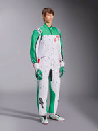 Kombinezon Alpinestars KMX-9 V3 Graphic 6, kombinezon kartingowy, biało-zielono-czerwony, noszony z dopasowanymi rękawicami i butami wyścigowymi, biały korpus z zielonymi rękawami i czarną grafiką typu splatter, czerwone logo Alpinestars na piersi, sportowy jednoczęściowy design do sportów motorowych.