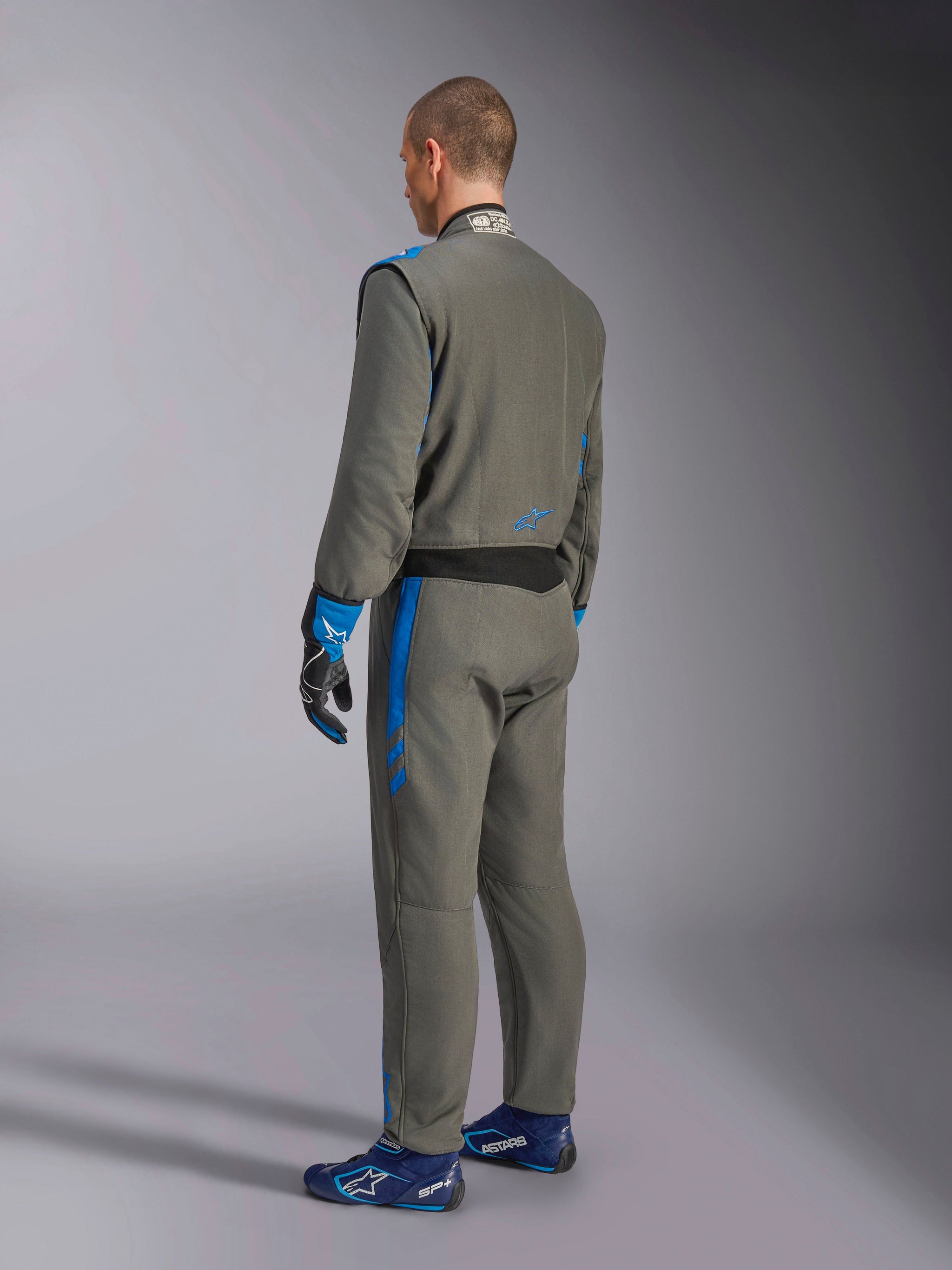 Alpinestars GP Race V3 Suit FIA, Auto Racing Suit, Anthracite Blue, rear view of model wearing the grey one-piece suit with blue accents, matching blue gloves and racing shoes, professional motorsport gear design