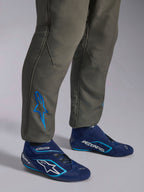 Alpinestars GP Race V3 Suit FIA, kombinezon samochodowy w kolorze Anthracite Blue, zbliżenie na dolną część nogawek z niebieskim haftowanym logo Astars na kostce, granatowe i błękitne buty wyścigowe, profesjonalna odzież ochronna do sportów motorowych