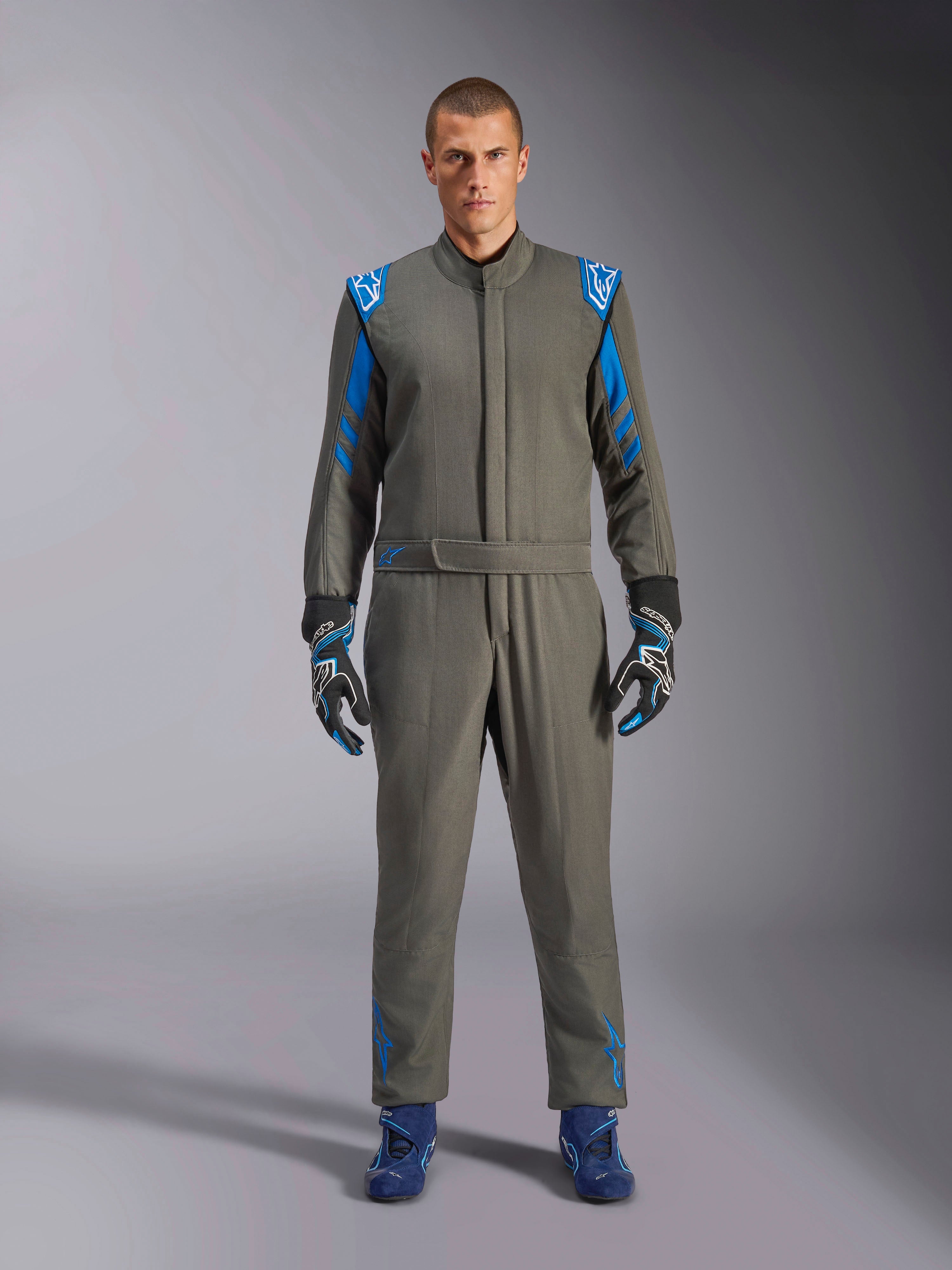 Alpinestars GP Race V3 Suit FIA, samochodowy kombinezon wyścigowy w kolorze Anthracite Blue, noszony z pasującymi rękawicami i butami wyścigowymi, jasnoniebieskie epolety na ramionach i paski na rękawach, detale z logo Alpinestars, profesjonalna ochrona do wyścigów torowych