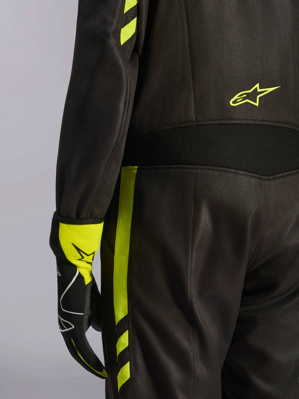 Alpinestars GP Race V3 Suit FIA, czarny i żółty fluorescencyjny, zbliżenie na talię i bok nogawki, aramidowe panele elastyczne i dopasowana rękawica wyścigowa, profesjonalna odzież do wyścigów samochodowych