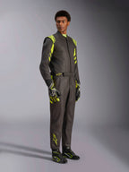 Alpinestars GP Race V3 Suit FIA, kombinezon samochodowy, czarno-żółty fluo, prezentowany przez modela z dopasowanymi rękawicami i butami wyścigowymi, jaskrawe żółte akcenty na ramionach i nogawkach, profesjonalna odzież motorsportowa