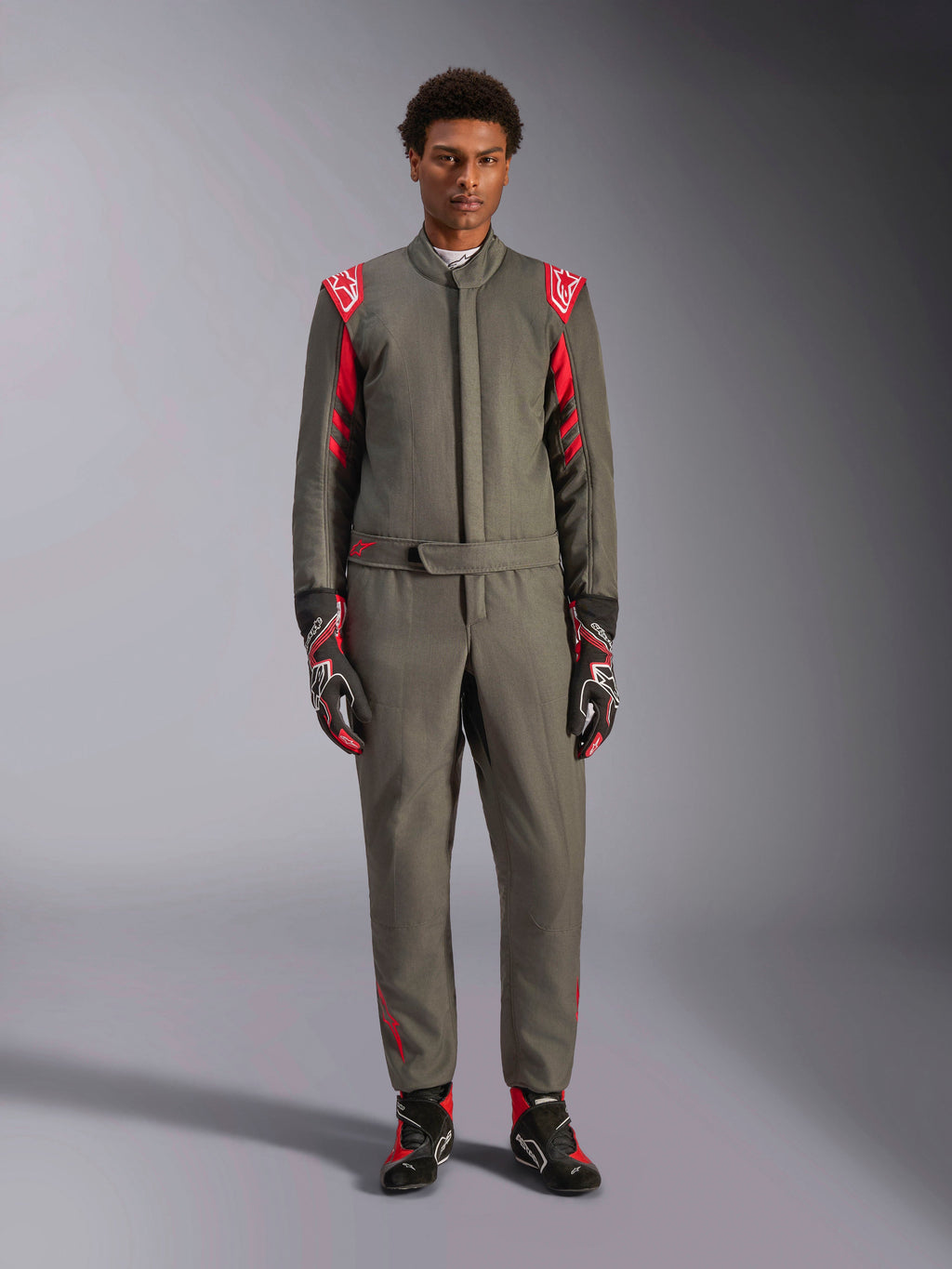 Alpinestars GP Race V3 Suit FIA, kombinezon samochodowy, antracytowo-czerwony, prezentowany przez modela z dopasowanymi rękawicami i butami, posiada czerwone epolety i logo marki, profesjonalna odzież do sportów motorowych.