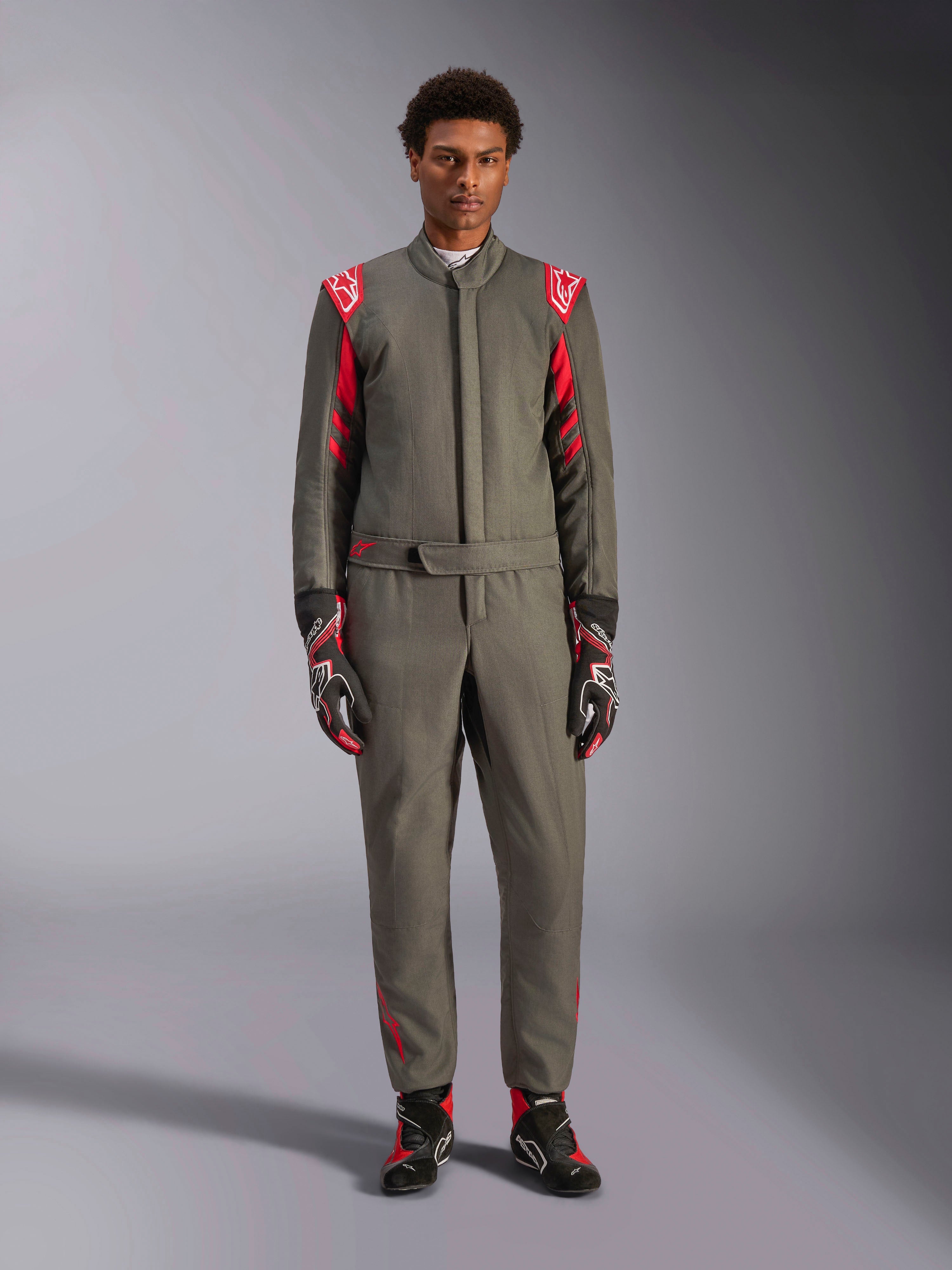 Alpinestars GP Race V3 Suit FIA, kombinezon samochodowy, antracytowo-czerwony, prezentowany przez modela z dopasowanymi rękawicami i butami, posiada czerwone epolety i logo marki, profesjonalna odzież do sportów motorowych.