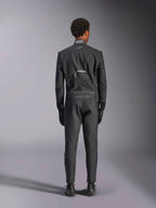 Kombinezon Alpinestars Hypertech V3, Black Dark Shadow, widok z tyłu profesjonalnego jednoczęściowego samochodowego kombinezonu wyścigowego, z etykietą certyfikacji FIA na kołnierzu oraz brandingiem „Alpinestars” i „RACING AHEAD” na dolnej części pleców, noszony z dopasowanymi czarnymi rękawicami i butami wyścigowymi.