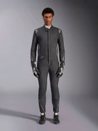 Alpinestars Hypertech V3 Suit, profesjonalny samochodowy kombinezon wyścigowy, czarny i Dark Shadow, prezentowany przez modela z dopasowanymi rękawicami i butami wyścigowymi, dopasowany sportowy krój ze srebrnymi akcentami i brandingiem, wyczynowa odzież motorsportowa