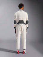 Widok z tyłu modela w kombinezonie Alpinestars Hypertech V3 w kolorze White Black Silver, prezentujący duży czarny elastyczny panel lędźwiowy z brandingiem „alpinestars” i „RACING AHEAD”, czarne wstawki na łokciach, etykietę certyfikacji FIA na kołnierzu oraz sportowy, dopasowany krój zaprojektowany do profesjonalnych wyścigów.