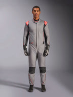 Alpinestars Hypertech V3 Suit, profesjonalny kombinezon wyścigowy w kolorze szarym, czarnym i jaskrawoczerwonym, prezentowany przez modela w czarnych rękawicach i butach wyścigowych, o sportowym, dopasowanym kroju, z jaskrawoczerwonymi akcentami na ramionach oraz czarnymi panelami na kolanach i po bokach.