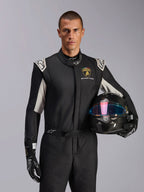 Model w kombinezonie Alpinestars Limited Edition Lamborghini GP Tech V4, czarny kombinezon wyścigowy ze srebrnymi akcentami i logo Lamborghini Squadra Corse, kask z włókna węglowego, czarne rękawice wyścigowe z białym logo, profesjonalny ubiór wyścigowy