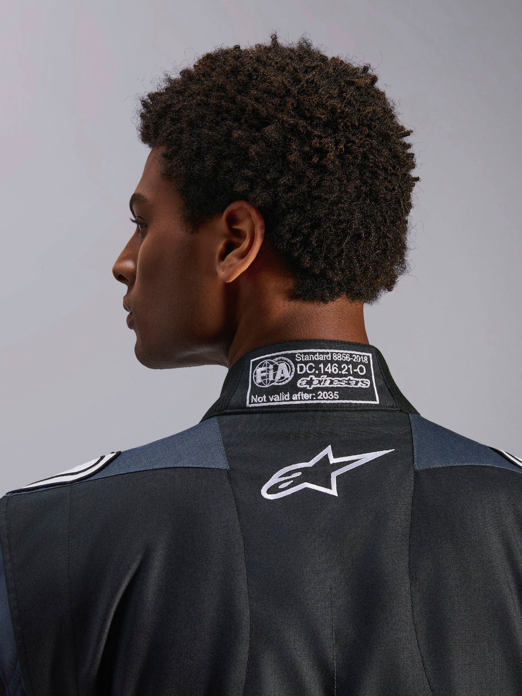 Alpinestars GP Pro Comp V2 FIA Suit, kombinezon samochodowy wyścigowy, czarny i asfaltowy, certyfikat FIA 8856-2018, białe logo Astar, zbliżenie na tył kołnierza.