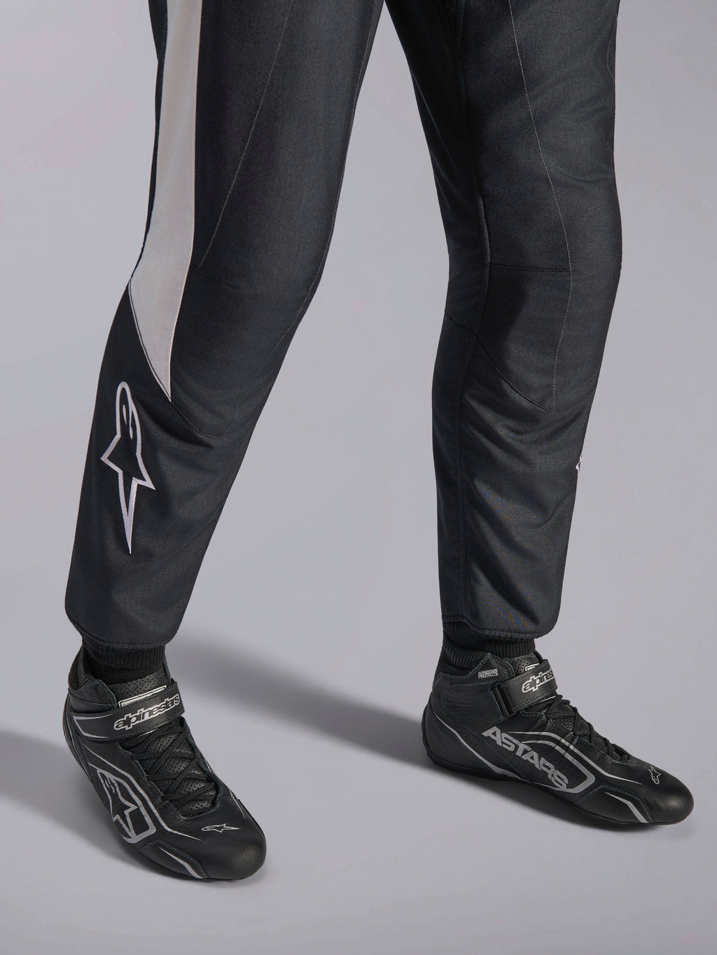 Kombinezon Alpinestars GP Pro Comp V2 FIA, czarny i biały strój wyścigowy, zbliżenie na buty ASTARS.