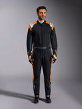 Alpinestars GP Pro Comp V2 FIA Suit, kombinezon samochodowy w kolorze czarnym i pomarańczowym fluo, męski model w pełnym stroju ochronnym z dopasowanymi rękawicami i butami wyścigowymi, białe logo Alpinestars i wyraziste pomarańczowe panele boczne, profesjonalna odzież motorsportowa
