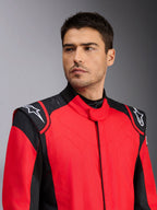 Męski model ubrany w kombinezon wyścigowy Alpinestars GP Pro Comp V2 FIA, czerwono-czarny, z białym logo Alpinestars na ramionach i detalami w technologii silicon grip, profesjonalna odzież do sportów motorowych