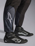 Kombinezon Alpinestars KMX-5 V3, Black Dark Shadow, zbliżenie na dolną część nogawek i kostki, białe logo gwiazdy na łydce, w połączeniu z czarnymi butami kartingowymi, dzianinowe ściągacze przy kostkach, sportowy-regularny krój