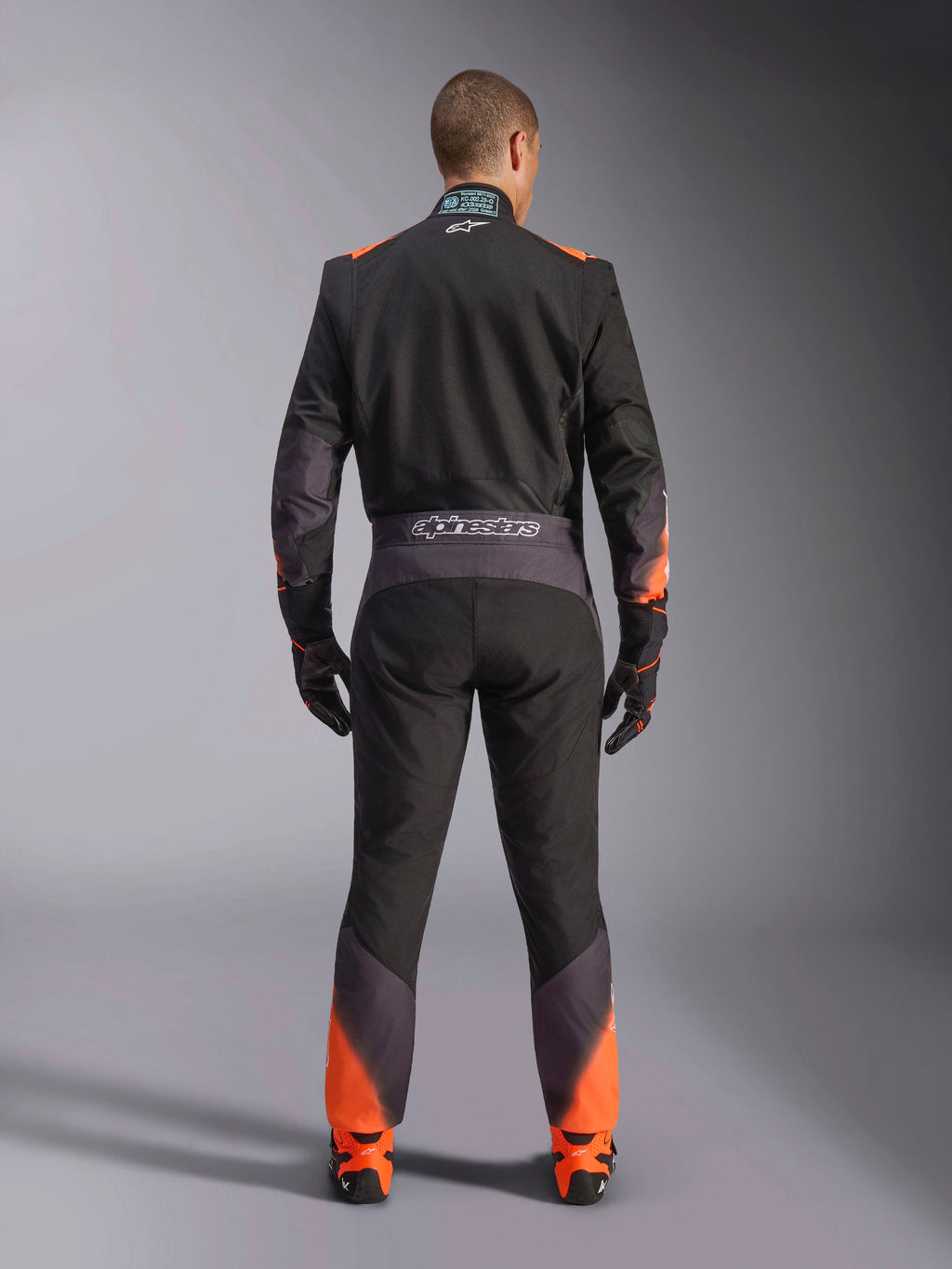 Kombinezon Alpinestars KMX-5 V3, męski kombinezon kartingowy, czarny i pomarańczowy fluo, certyfikat FIA, widok tyłu z logo.