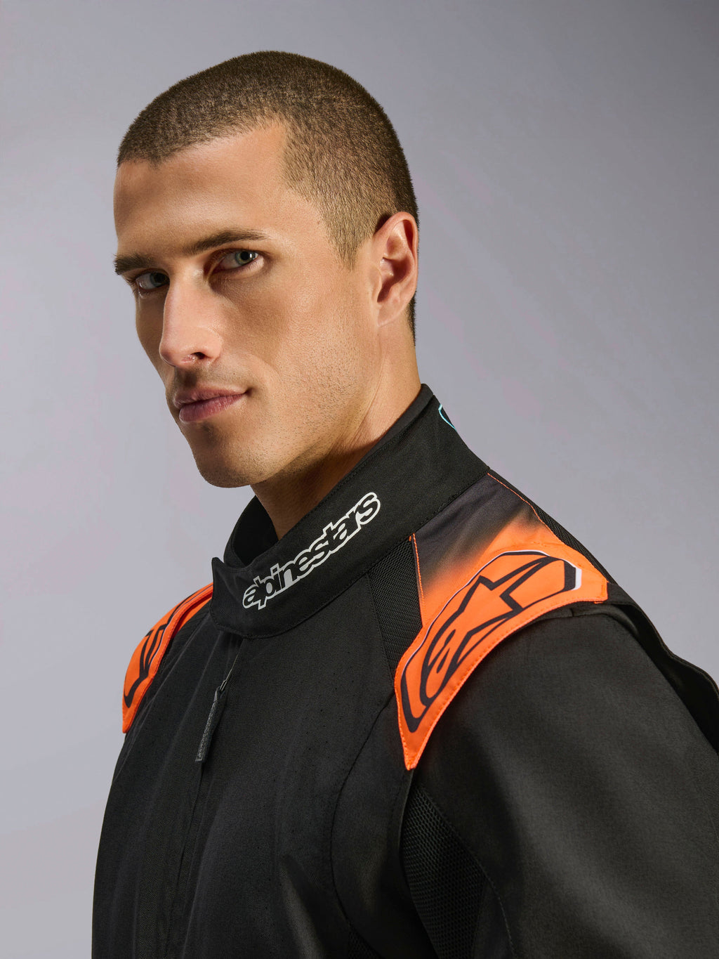 Kombinezon kartingowy Alpinestars KMX-5 V3, czarny i pomarańczowy fluo, zbliżenie na kołnierz i ramiona na modelu.