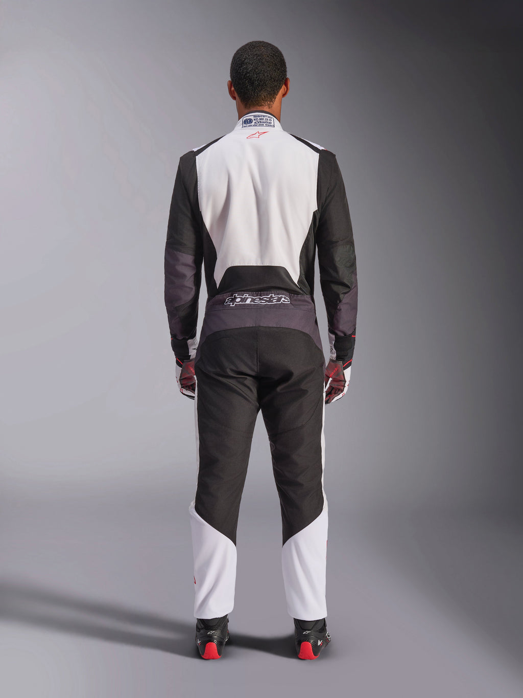 Kombinezon Alpinestars KMX-5 V3, kombinezon kartingowy, biały, czarny i jaskrawoczerwony, widok z tyłu, jednoczęściowy kombinezon wyścigowy z oddychającymi panelami z siatki i logo Alpinestars w pasie, noszony z pasującymi rękawicami i butami wyścigowymi