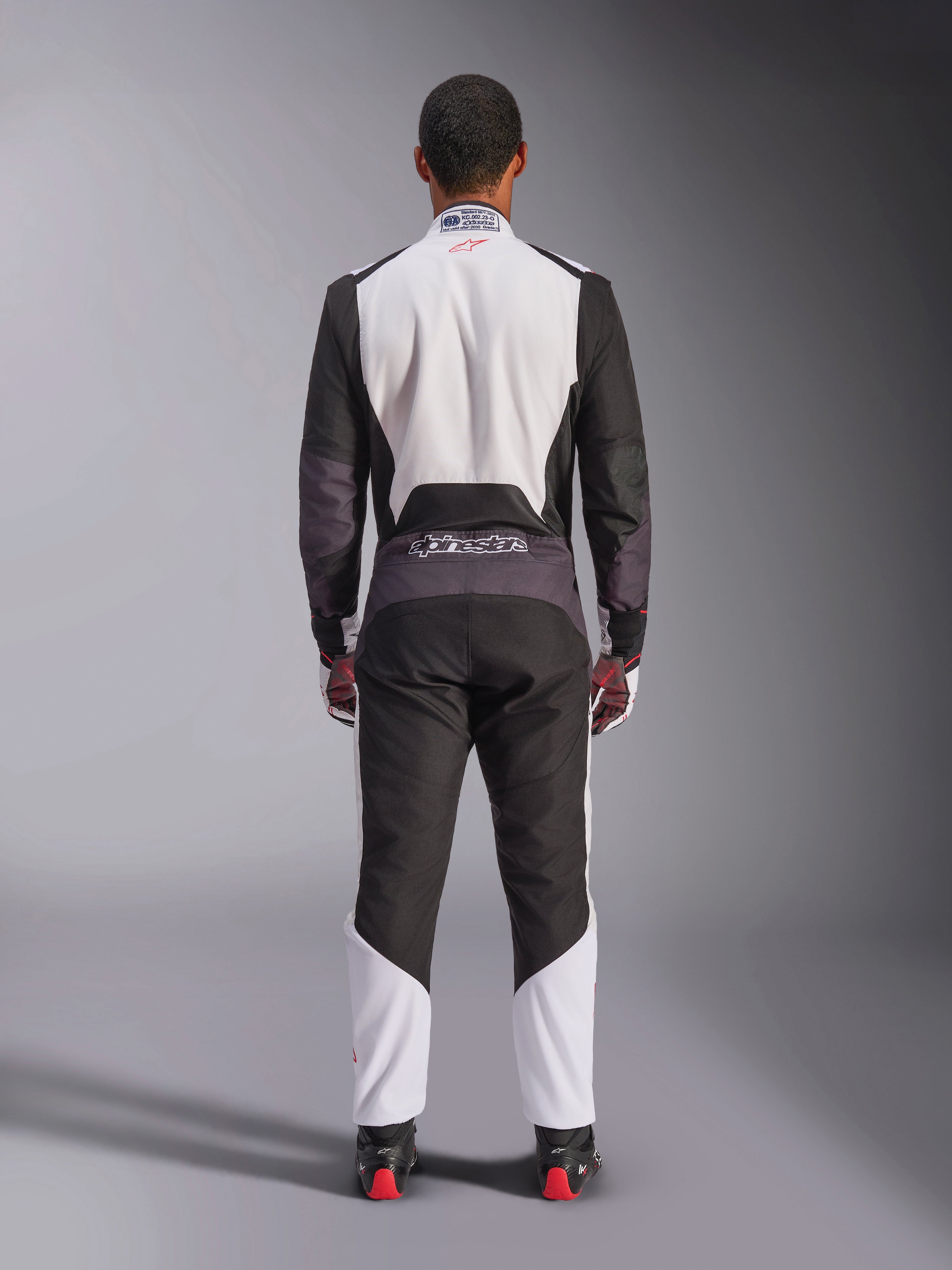 Kombinezon Alpinestars KMX-5 V3, kombinezon kartingowy, biały, czarny i jaskrawoczerwony, widok z tyłu, jednoczęściowy kombinezon wyścigowy z oddychającymi panelami z siatki i logo Alpinestars w pasie, noszony z pasującymi rękawicami i butami wyścigowymi