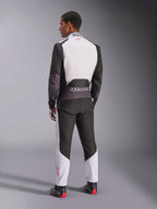 Kombinezon Alpinestars KMX-5 V3, kombinezon kartingowy, biały, czarny i jaskrawoczerwony, widok z tyłu na mężczyznę w jednoczęściowym kombinezonie wyścigowym z białą górną częścią pleców i czarnymi dolnymi panelami, małe czerwone logo na kołnierzu, profesjonalne buty i rękawice wyścigowe