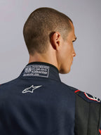 Kombinezon Alpinestars GP Tech V4 w kolorze granatowo-czarno-czerwonym, zbliżenie na tylny kołnierz z etykietą certyfikacji FIA 8856-2018 i białym haftowanym logo Alpinestars, detale wysokowydajnego kombinezonu wyścigowego