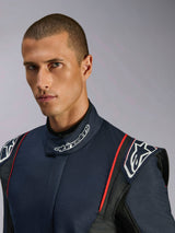 Portret z bliska modela ubranego w kombinezon Alpinestars GP Tech V4, samochodowy kombinezon wyścigowy w kolorze granatowym, czarnym i czerwonym, z logo Alpinestars na wysokim kołnierzu i ustrukturyzowanymi naramiennikami.