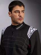 Alpinestars KMX-9 V3 Suit, Black Karting Suit worn by a male model, close-up of chest and shoulders with white branding on the collar and epaulettes, featuring white decorative stitching and a professional motorsport design