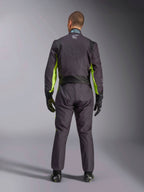 Widok od tyłu na całą sylwetkę osoby ubranej w kombinezon kartingowy Alpinestars KMX-9 V3 Graphic 3 w kolorze czarnym i żółtym fluo, widoczne ergonomiczne panele rozciągliwe na plecach i ramionach, czarne rękawice i buty wyścigowe.