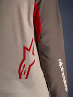 Alpinestars Maxdura Dual Jersey, Aluminum Walnut, zbliżenie na wentylowany siatkowy tors z czerwonym logo gwiazdy i brązowy rękaw odporny na ścieranie z białym napisem Alpinestars, techniczna odzież motocyklowa adventure i dual-sport