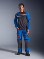 Alpinestars Maxdura Dual Jersey, koszulka motocyklowa, ciemnoszara i królewski błękit, tułów z pełnej siatki, wyściełane rękawy i kieszenie na piersi na zamek, białe i pomarańczowe logo Alpinestars, noszona z dopasowanymi spodniami adventure i czarnymi butami