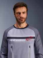 Alpinestars Maxdura Dual Jersey, Mid Gray and Dark Gray, worn by male model, featuring a mesh torso for ventilation, dual zippered chest pockets, white 'alpinestars' branding and red star logo, performance off-road adventure gear